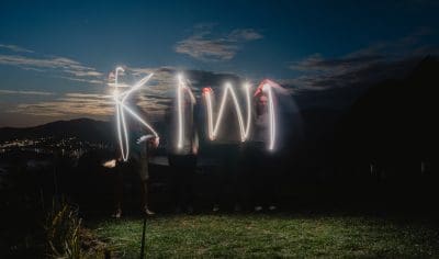 A diverse group of friends uses glowing sparklers to write illuminated words in the night, creating vibrant light trails and festive energy.