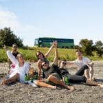 A diverse group of friends relaxes together on a pristine sandy beach, enjoying sunbathing and sea views under a clear blue sky.
