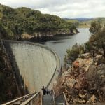 Visitors descend stairs towards the iconic Gordon Dam in Lake Pedder Wilderness on a guided small group tour beneath overcast skies.