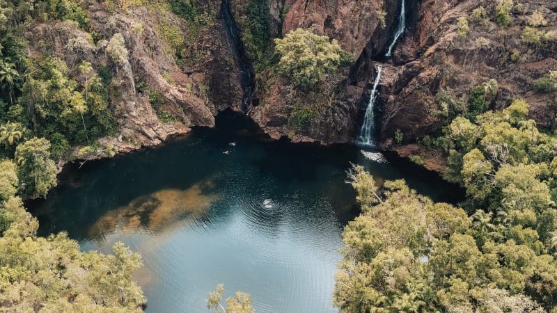 Stunning aerial view of a waterfall cascading into a rocky pond on a 5 Day Kakadu, Katherine Gorge, Litchfield 4WD Adventure from Darwin.