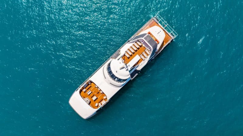 Aerial photo of a luxurious white yacht with brown decks at Whitehaven Beach, showcased all day; no snorkelling permitted on-site.
