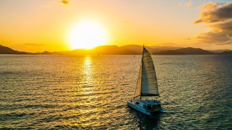 Experience a stunning sunset sailboat cruise near Airlie Beach with shimmering golden reflections—BYO and enjoy style on the water.