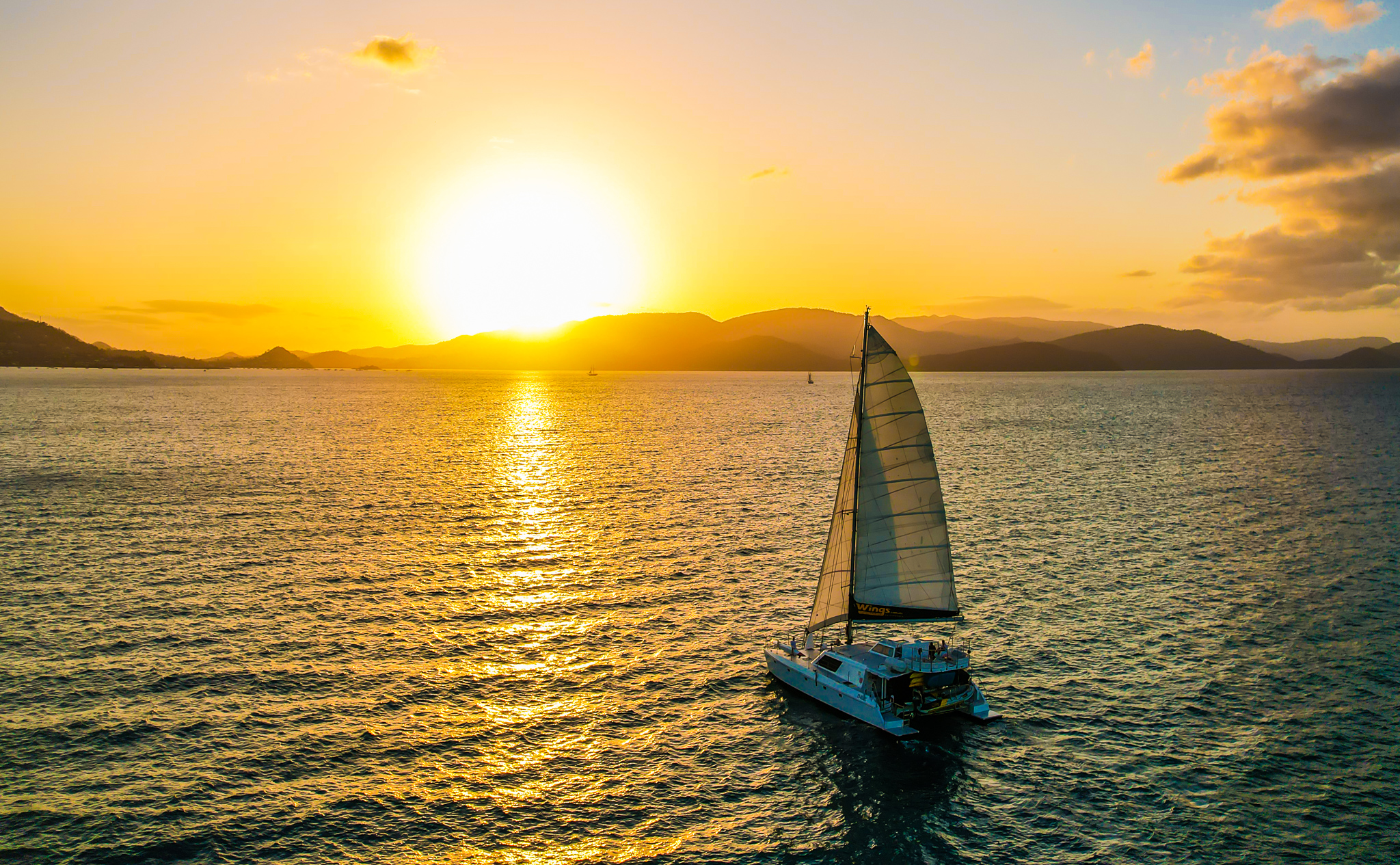 Experience a stunning sunset sailboat cruise near Airlie Beach with shimmering golden reflections—BYO and enjoy style on the water.