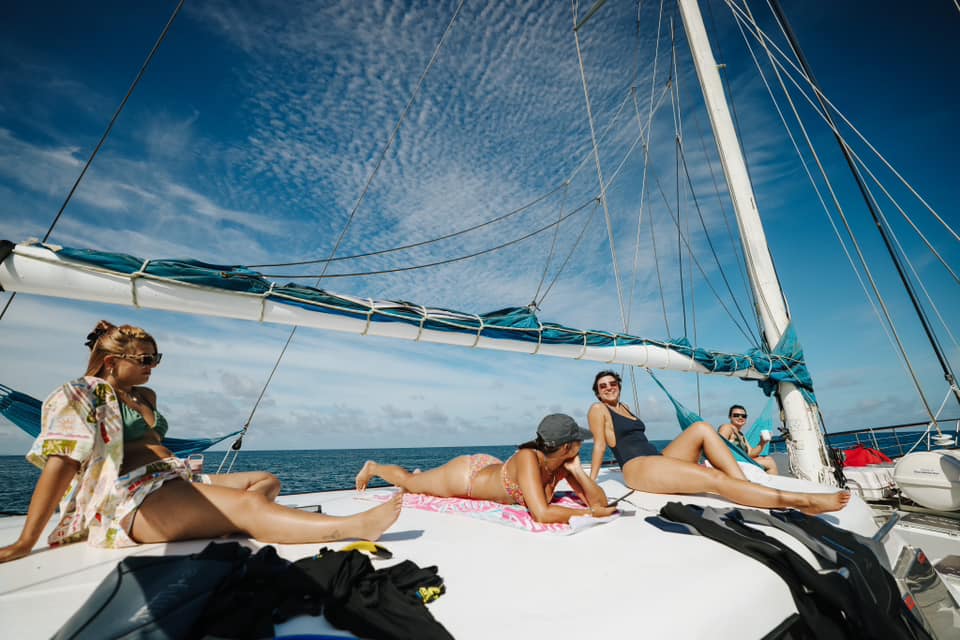 Experience four people relaxing aboard the Summer Jo Day Charter sailing boat beneath a bright blue sky with wispy clouds over the sea.