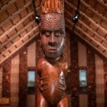 Intricately tattooed wooden Māori carving in a traditional meeting house at Waitangi Treaty Grounds, historic site in New Zealand.