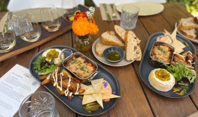 Elegant outdoor table set with artisanal appetisers, fresh bread, and detailed wine menus on a Boutique Wine Tour experience.