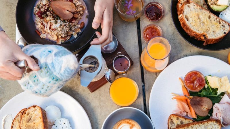 Sumptuous breakfast spread on a table as tea is poured, inviting you to start your 8 Day Sydney to Brisbane Fraser Island tour.