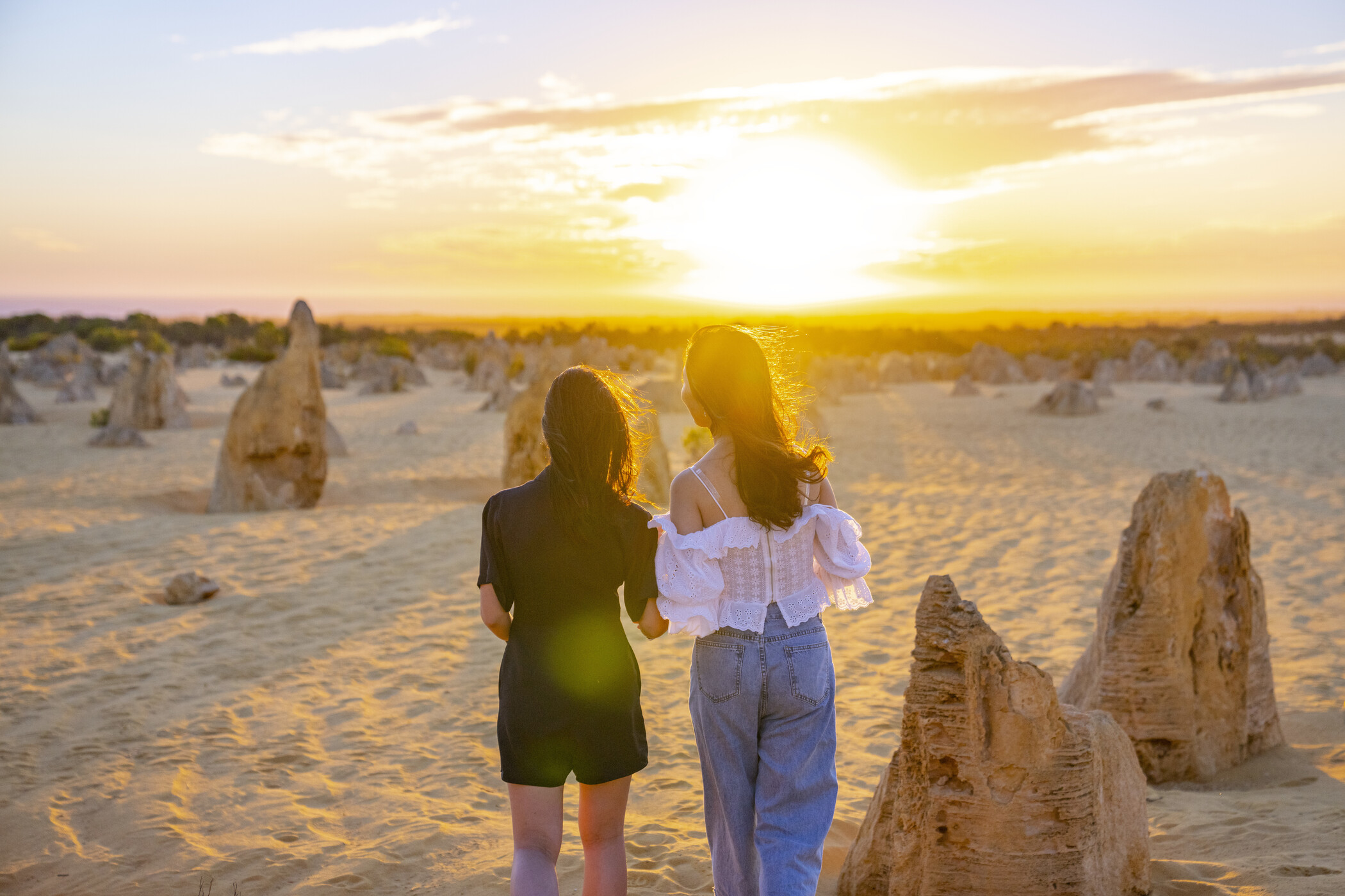Experience the breathtaking 1 Day Pinnacles Sunset Stargazing Tour by Autopia as two travellers explore sandy desert dunes at sunset.