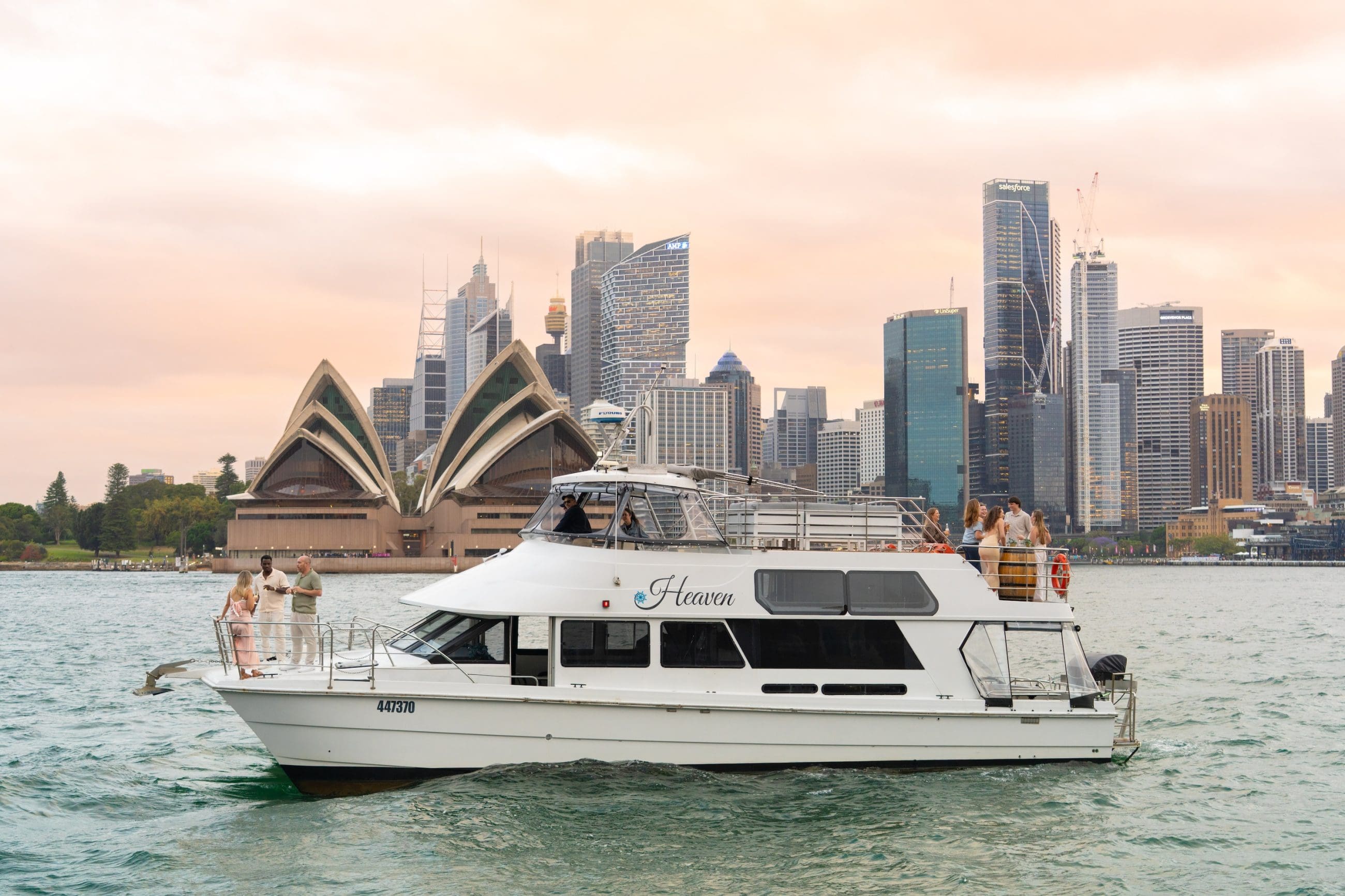 White boat with passengers cruises Sydney Harbour at sunset, golden skies behind Opera House and skyline for iconic Australian views.