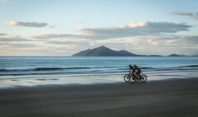 Couple biking on the sand along Mission Beach with ocean in the background