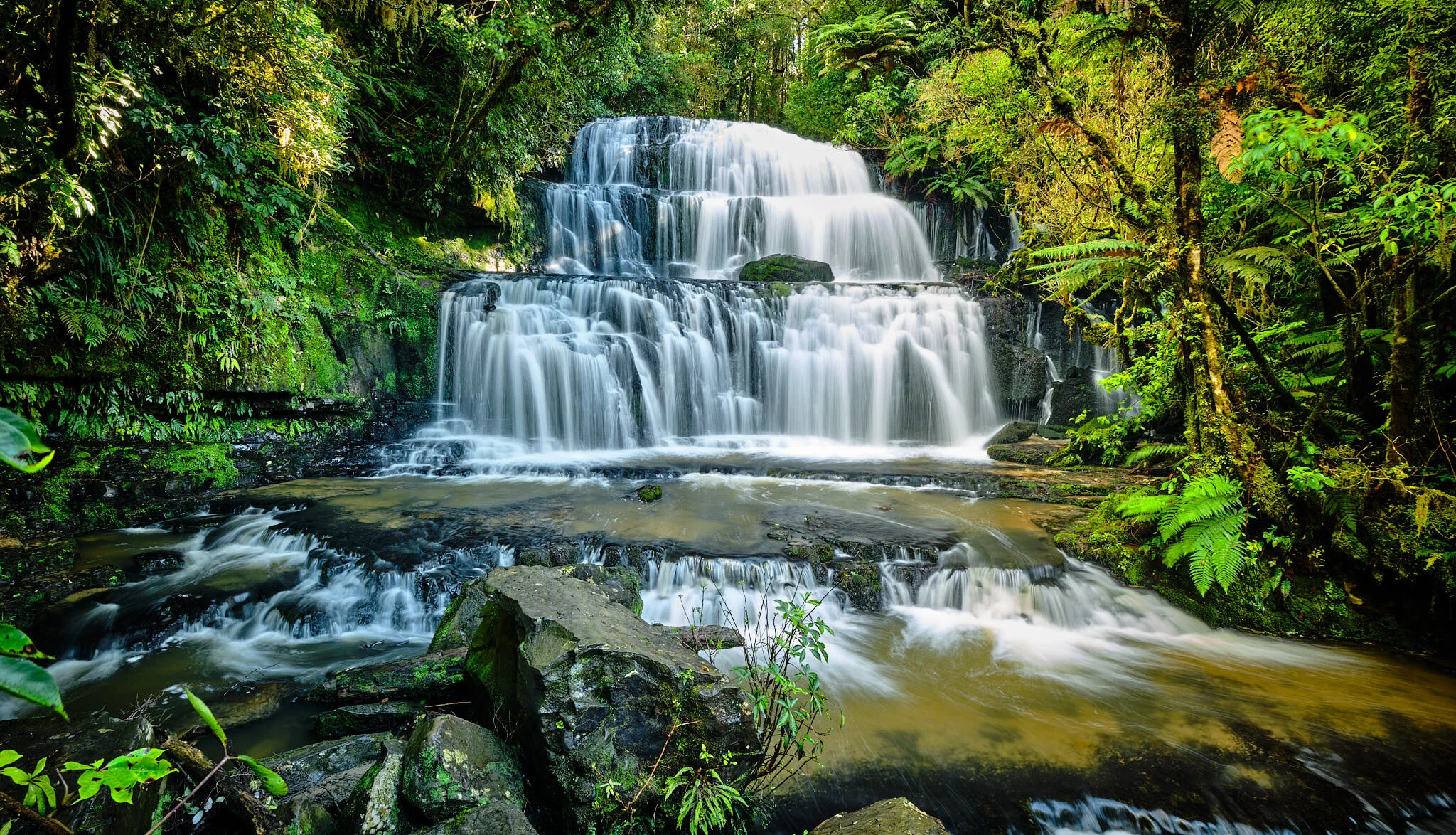 3 tiered waterfall cascading down surrounded by green trees