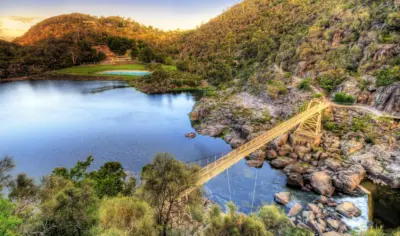 beautiful bridge over water at sunset between two hilly green sides