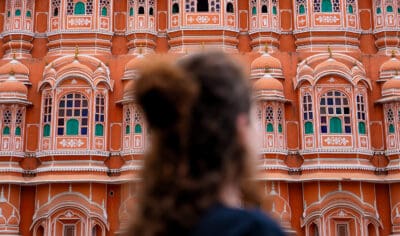 A woman standing in front of a colourful building in India.
