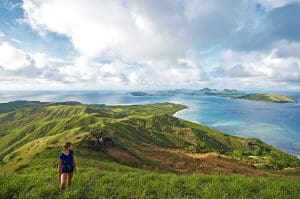 Image of backapcker hiking a beautiful mountain in Fiji whilst admiring the stunning views overlooking the Ocean