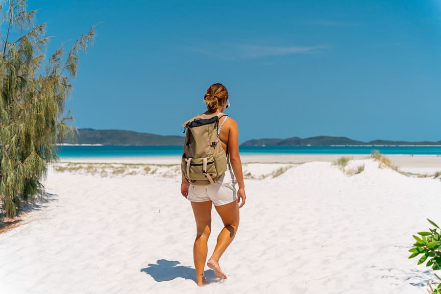 girl with backpack walking on whitehaven beach whitsundays